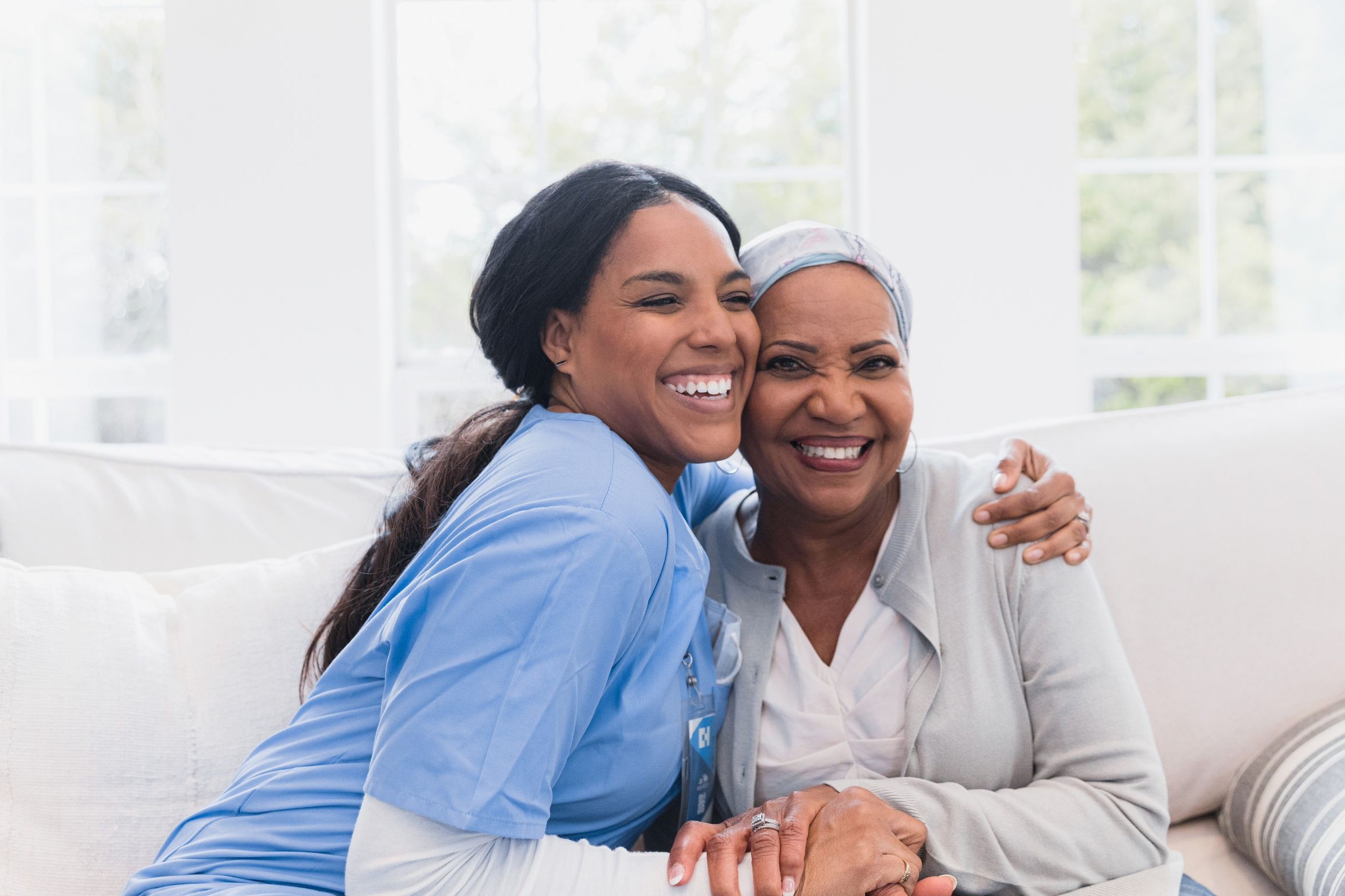 Caregiver embracing and comforting an elderly woman at home